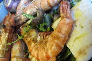 Тигровые креветки с табаско, лимоном и чесноком на листовой подушке с теплой питой